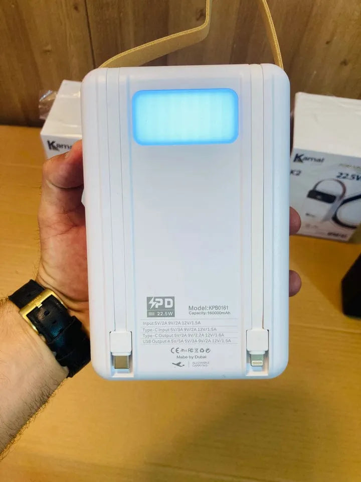 Hand holding a white electronic device with a digital display on a wooden surface.