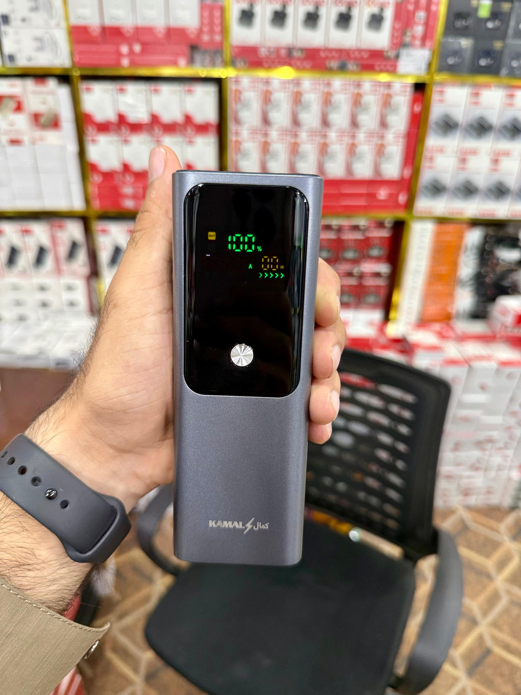 Hand holding a digital device with a screen in a store setting